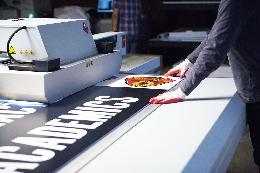 A sign being printed on the flatbed UV printer in the Church Sign Shop print shop